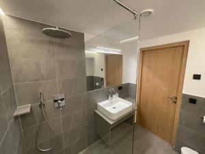La salle de bains est pourvue d'un lavabo et d'une douche. dans l'établissement Dorfblick Appartements & Rooms, à Senales