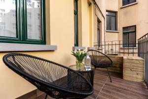 a balcony with two chairs and a table with flowers at CA’MILLA Luxury Apartments Trieste in Trieste