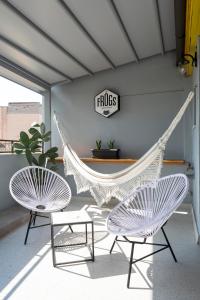 2 stoelen en een hangmat in een kamer met een bord bij The Frogs_Guest House in Athene