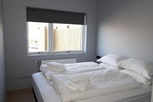 een bed met witte lakens en kussens en een raam bij Tryggvabraut 24 One Bedroom Apartment in Akureyri