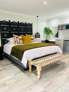 a bedroom with a large bed and a bench at Impa-Lala Country Estate in Bloemfontein