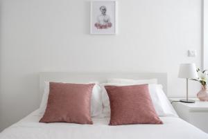 um quarto com uma cama branca e 2 almofadas vermelhas em Casas Peralta - Marialva em Arouca