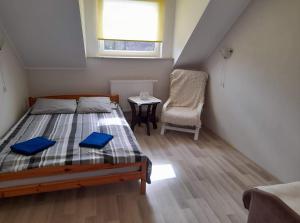 um quarto com uma cama, uma cadeira e uma janela em Pensjonacik Marzenie em Klonowo Dolne