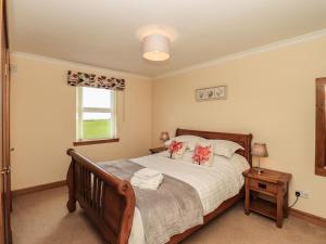a bedroom with a large bed and a window at Challochmun Bungalow in Newton Stewart