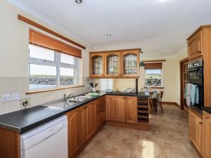 a kitchen with wooden cabinets and black counter tops at Challochmun Bungalow in Newton Stewart