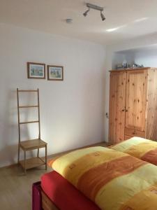 ein Schlafzimmer mit einem Bett, einem Holzschrank und einem Stuhl in der Unterkunft Ferienwohnung Roder in Marburg an der Lahn