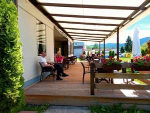 personas sentadas en el porche de un edificio en Hotel Drinska lasta en Ljubovija