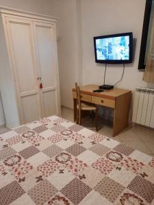 una camera con letto, scrivania e TV di Foresteria Guest House a Gaiole in Chianti