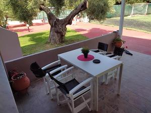 a white table and chairs on a patio with a tree at Christos House in Neos Marmaras