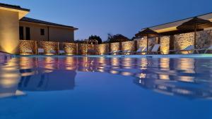 a swimming pool at night with chairs and umbrellas at Résidence Storia d'Estate in LʼÎle-Rousse