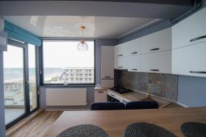 eine Küche mit weißen Schränken und einem großen Fenster in der Unterkunft Apartel Marina in Mamaia Nord – Năvodari