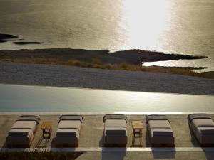 a row of beds on a beach with the ocean at Domes White Coast Milos, Adults Only - Small Luxury Hotels of the World in Mytakas