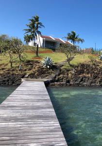 a wooden boardwalk over the water in front of a house at LA COLLINE DU LAGON in Le François