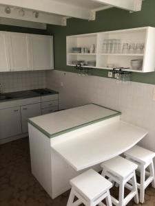 una cucina con bancone bianco e sgabelli bianchi di LA COLLINE DU LAGON a Le François