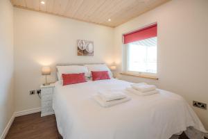 um quarto branco com uma grande cama branca com almofadas vermelhas em Stargaze em Great Yarmouth