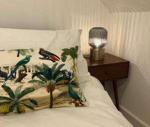 a bed with a pillow with parrots and a lamp at Castle Nook in Kelso