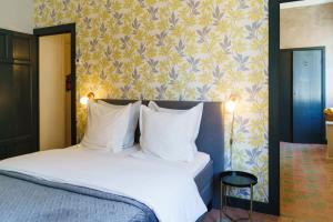 1 dormitorio con cama con almohadas blancas y papel pintado en Logement Onze Chambres & Gîtes, en Raissac-dʼAude