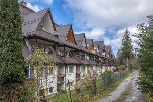 una fila de casas con una valla y un camino de tierra en Rent like home - Za Cieszynianką 5 en Zakopane