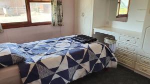 a bedroom with a bed and a desk and window at Huntersfield Chalet in Faringdon