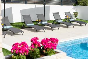 a row of chairs and tables next to a pool at Apartments Corcovado with Heated Pool in Vodice +74 photos