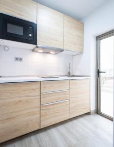 eine Küche mit Holzschränken und einer Mikrowelle in der Unterkunft Etti Paradise Suite Mediterraneo in Pájara