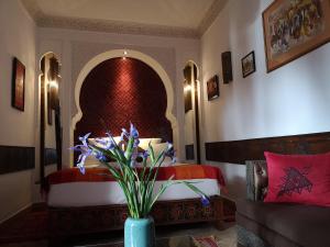 Un dormitorio con una cama y un jarrón con flores. en Riad Charme d'Orient Adults Only, en Marrakech