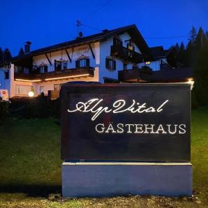 a sign in front of a house with a building at Gästehaus Alpvital in Klais