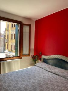 a red bedroom with a bed and a window at Hotel San Geremia in Venice