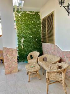 un patio con sillas de mimbre y una pared verde en Il Mare in Tasca - Casa Vacanze - loc.Torre Lapillo (LE) - Salento, en Torre Lapillo