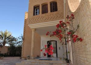 a building with red flowers on the side of it at Maison D'Hôtes villa Fatima in Tozeur
