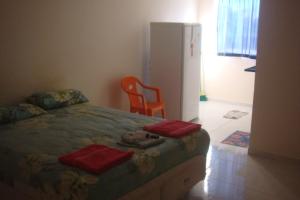 a bedroom with a bed and a chair and a refrigerator at stellamares suites in Salvador
