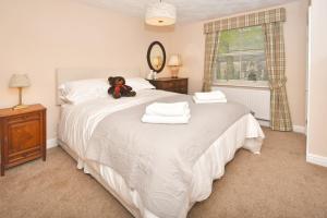 un osito de peluche sentado en una cama en un dormitorio en The Fountain Inn, en Leek