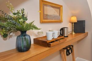 una estantería de madera con un jarrón de flores. en The Fountain Inn, en Leek