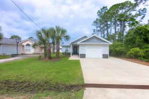 a house with a driveway and palm trees at Three Palms Tree Home in Panama City Beach