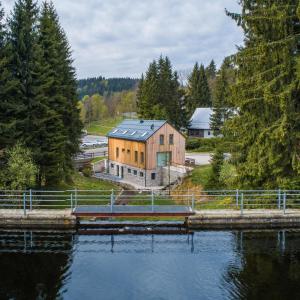 a house with a solar roof on top of a body of water at Apartmány Bílá Nisa in Bedřichov