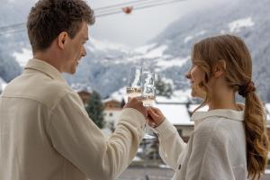 een man en een vrouw met een glas wijn bij Strass - Sport & Spa Hotel in Mayrhofen