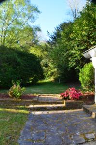 una pasarela de piedra en un jardín con flores rosas en Lodge Kervoazec - Château de Kervoazec, en Saint-Goazec