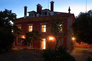 una gran casa roja con luces encendidas por la noche en Casa de Santa Teresa en Estoril