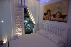 ein weißes Schlafzimmer mit einem Bett und einem Fenster in der Unterkunft La Dolce Notte in Matera