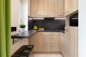 a kitchen with wooden cabinets and a black counter top at Apartament Zielony Sopot Karlikowo by Renters in Sopot