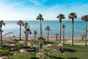a view of a beach with palm trees and umbrellas at Radisson Collection Hotel, Bodrum in Akyarlar