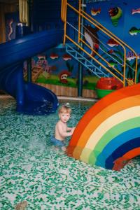 een jonge jongen in het water bij een waterglijbaan bij Alice Place Hotel in Odessa