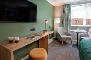 a living room with a couch and a tv at Horwood House Hotel in Milton Keynes