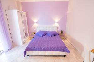 a purple bedroom with a bed with purple sheets and pillows at ΒΟΛΤΑ στουντιο στην καρδιά της Πρεβεζας in Preveza