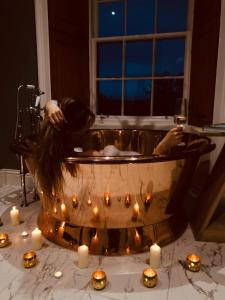 una persona en una bañera con velas y una copa de vino en Forss House en Thurso