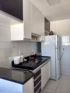 La cuisine blanche est équipée d'un évier et d'un réfrigérateur. dans l'établissement Edifício Gil Nogueira, apartamento aconchegantes, piscina, sauna, Wiff, duas vagas de garagem., à Guarapari