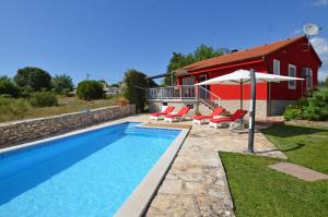 a pool with chairs and an umbrella next to a house at Villa Ketty in Kanfanar