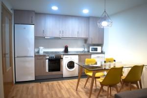 a kitchen with white appliances and a table with chairs at Guest House Ainsa Pirineos in Aínsa
