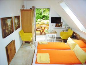 um quarto com uma cama laranja e cadeiras amarelas em Ostsee Hotel-Pension An der Lindenallee em Bad Doberan
