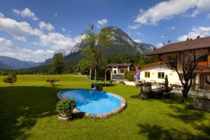 un patio con una piscina con una casa y montañas en Gästehaus Baltram, en Ramsau